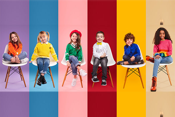 Cheerful kids in stylish clothes sitting on chairs