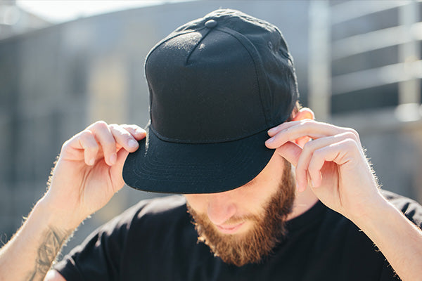 Hipster handsome male model with beard wearing black blank baseball cap 