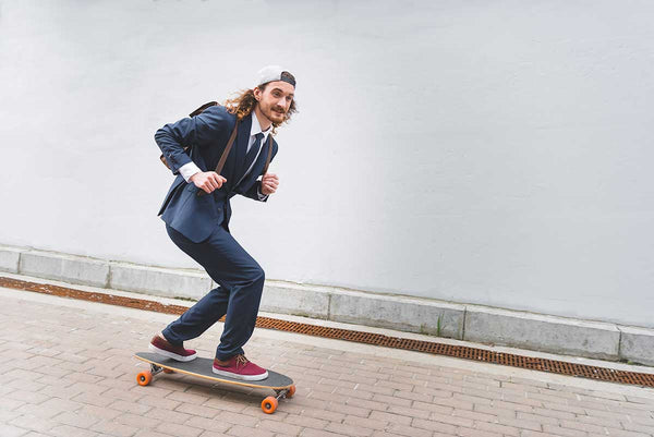 happy and handsome businessman riding on skateboard at street