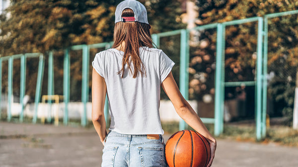 Pretty young girl holding basketball ball, rear view