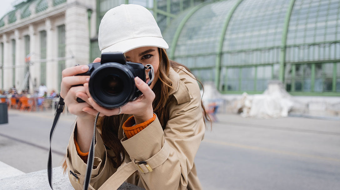 Young photographer in trench coat and baseball cap